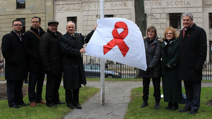 Health Minister Leo Glavine raisies a red ribbon flag for AIDS Awareness Week