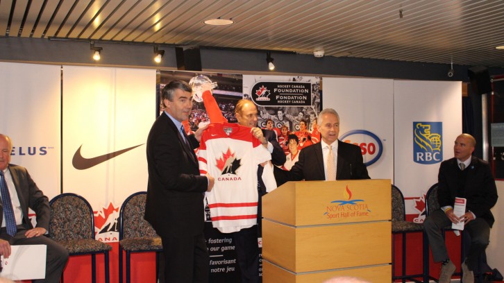Jim Treliving & CEO of Hockey Canada, Tom Renney, present Premier McNeil with Hockey Canada jersey 