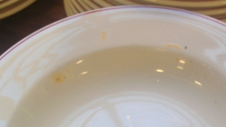 A plate with dried food stains in a stack of clean plates in Prince Hall. 