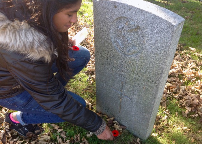 Grade nine students pay tribute to Canada's fallen soldiers by placing a poppy at the foot of each headstone.