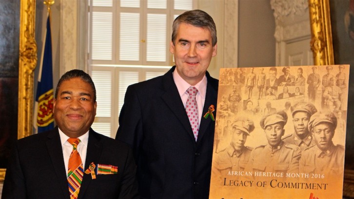 Minister of African Nova Scotian Affairs Tony Ince and Premier Stephen McNeil stand with the official poster for African Heritage Month 2016.