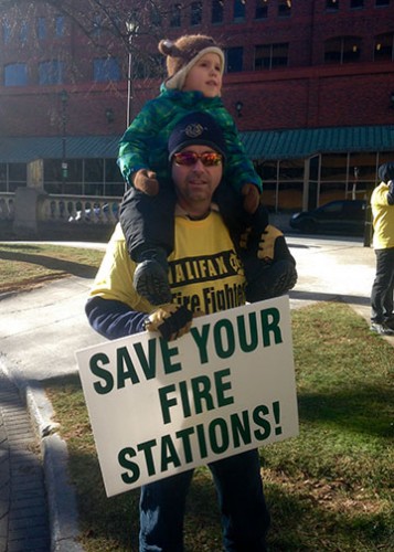 Brad Simms, a firefighter from Station 2 on University Avenue, and his son Benjamin protested outside City Hall.