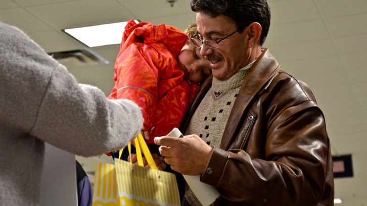 Sponsors hand a gift bag to a refugee family at the Halifax airport