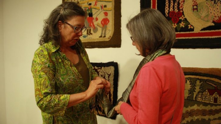 Liza Hageraats, left, explains a rug hooking technique to Carolyn Harry