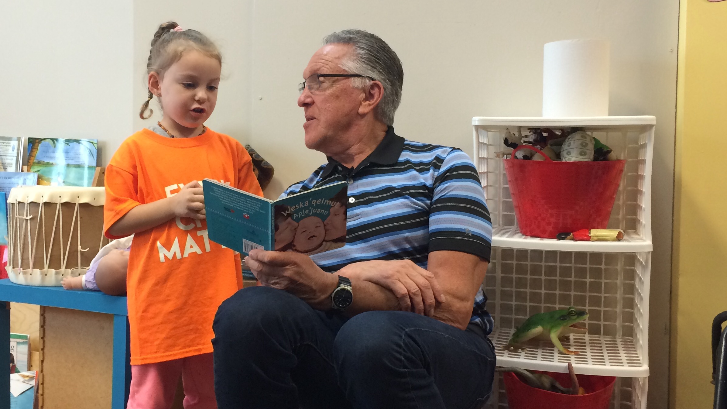 Bernie Francis reads in Mi'kmaq to four-year old Brielle Pennell.
