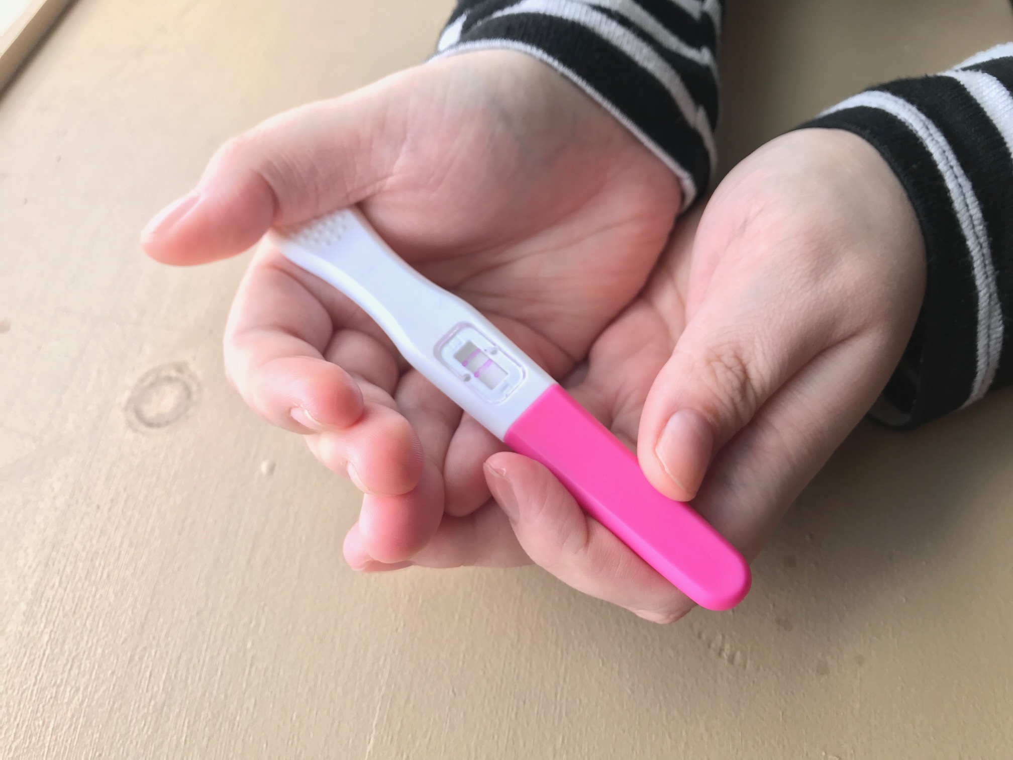A woman's hands hold a pregnancy test.