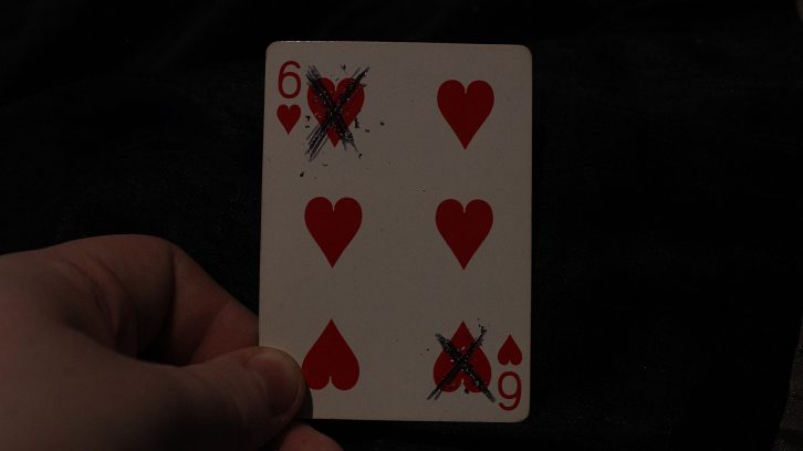 A six of hearts card with two of the hearts crossed out