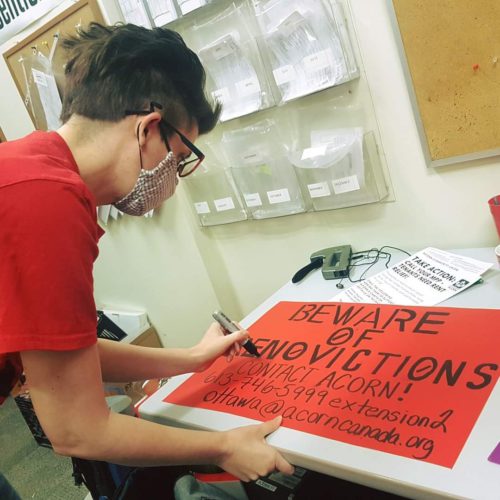 Photo of a woman in a red T-shirt drawing a sign
