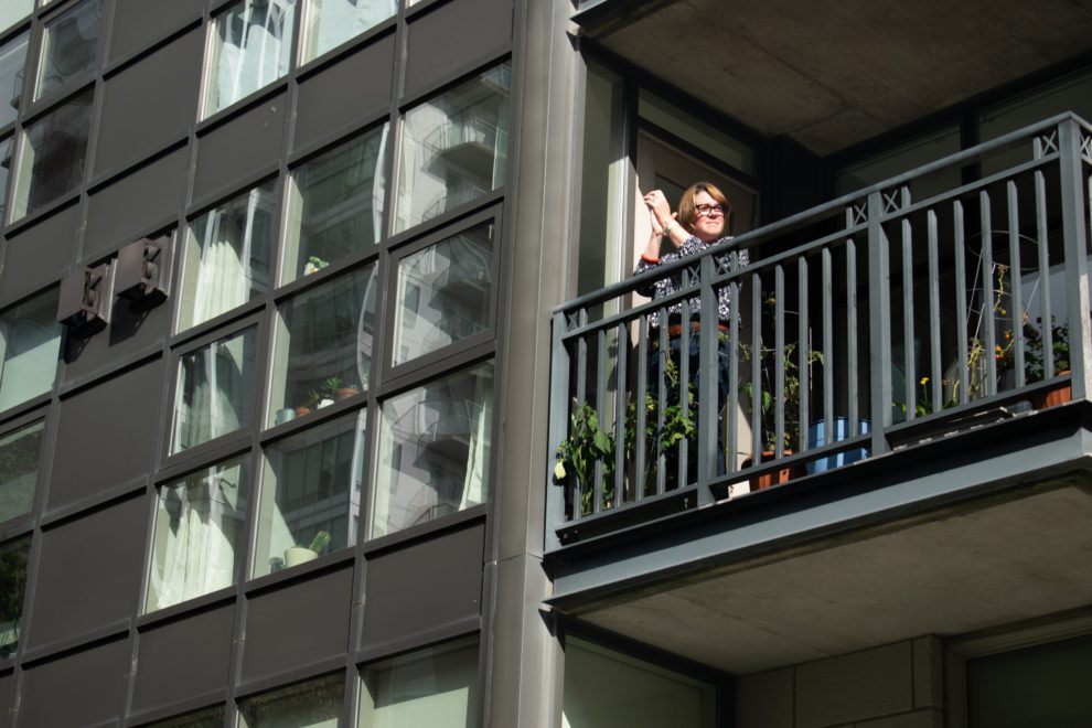 A woman cheers and applauds from her condo balcony as climate strikers march along Lower Water Street in downtown Halifax.