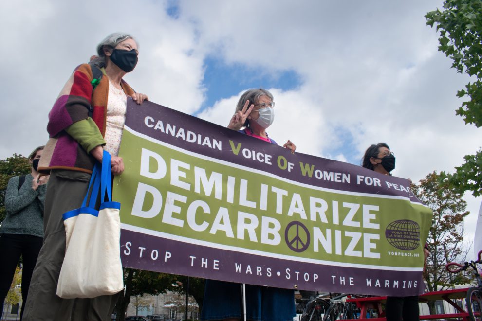 The Raging Grannies of Nova Scotia hold up a banner denouncing militarization along with the use of fossil fuels at the Halifax climate strike
