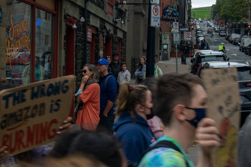 Passers-by stop and look as climate strikers march by Prince Street in downtown Halifax.