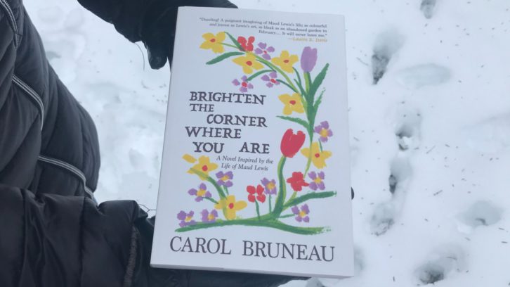 Hands holding a novel titled Brighten the Corner Where you Are against a snowy background.