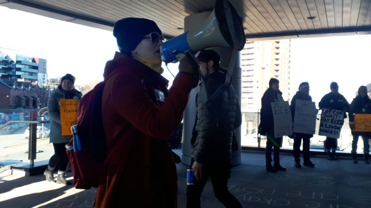 A woman in a red coat holding a megaphone.