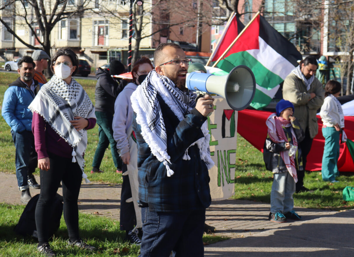 A man speaking with a megaphone at a protest.