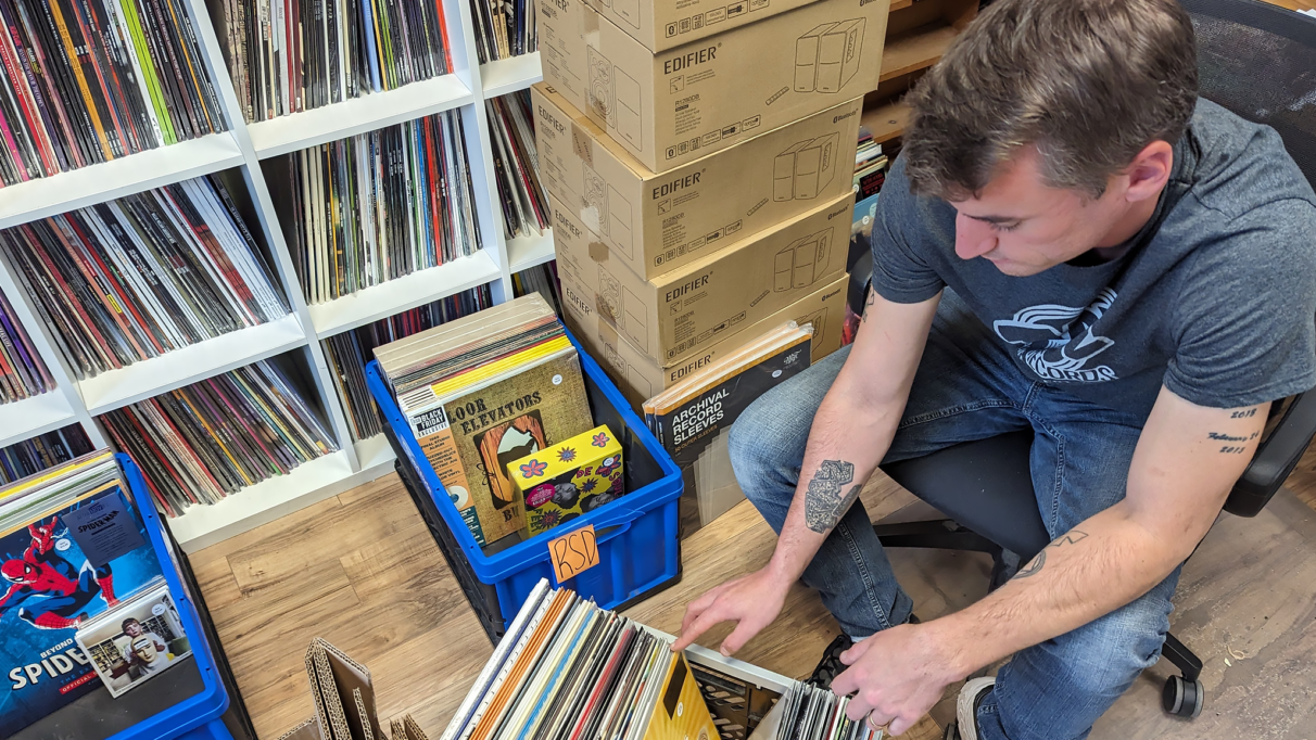 Jimmy Donnelly, the owner of Taz Records in Halifax, sits in his office chair while flipping through records in a crate on the floor.