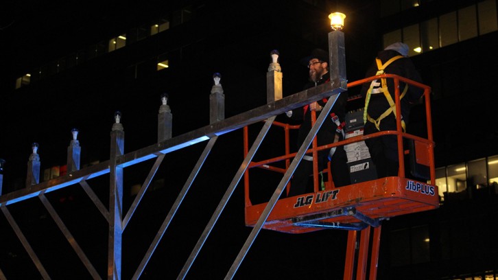Rabbi Mendel Feldman lights a large menorah in Grand Parade Square on Monday evening.