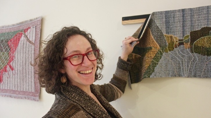 Textile artist Rilla Marshall peels a handwoven map from its mount at the Mary E. Black Gallery downtown.
