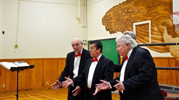A tuxedo-clad barbershop quartet singing.