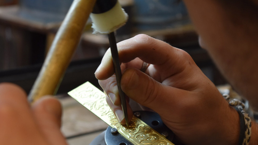 Nicholas Rosin engraves a bracelet with a hammer and chisel.