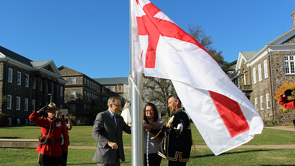 Dalhousie President Richard Florizone (L), Dalhousie science student Melanie Hardie (centre) and Grand Keptin Andrew Denny of the Mi'kmaq Grand Council raise the Grand Council Flag together