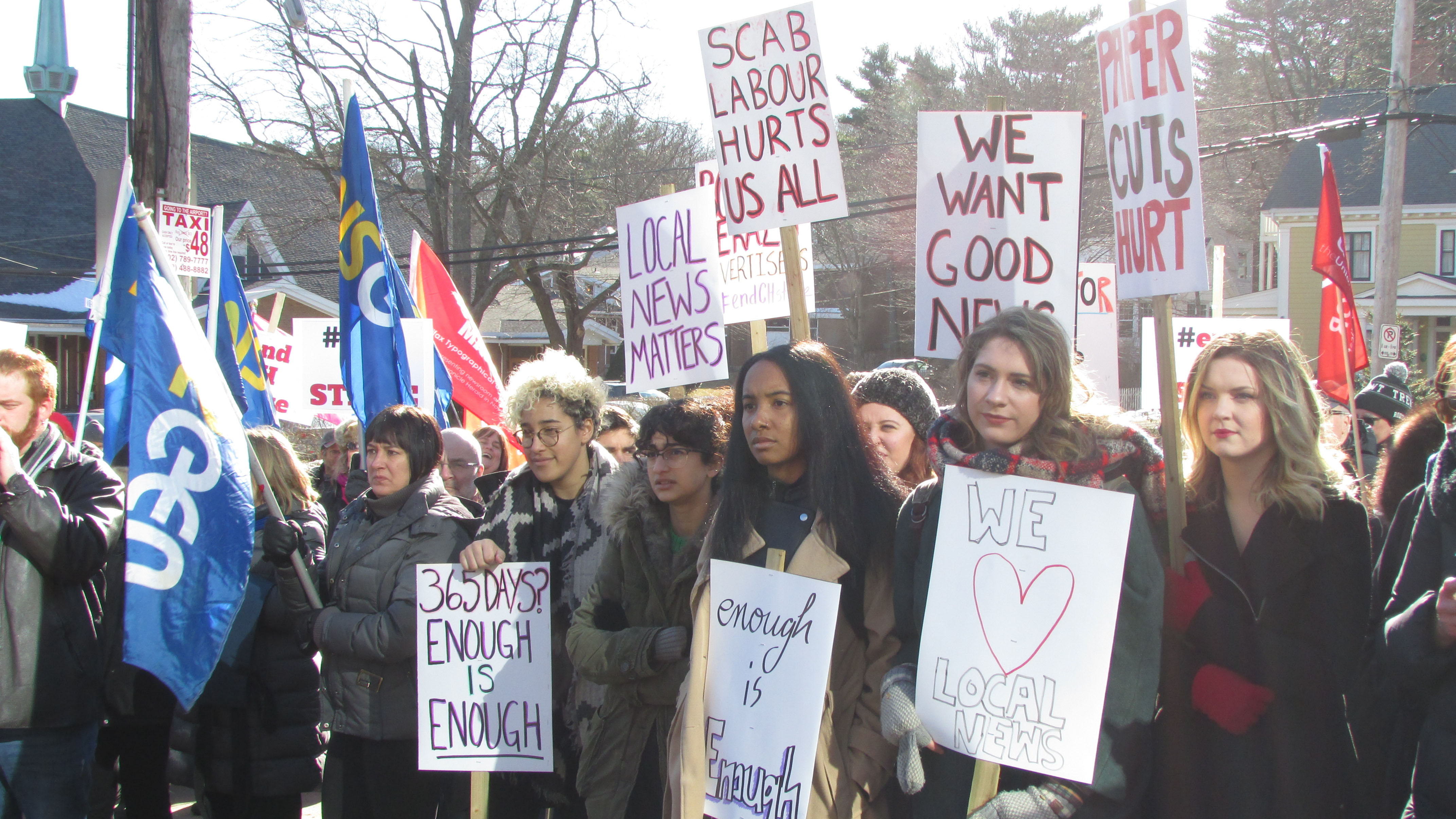 People of all ages gathered at the Chronicle Herald protest holding signs and flags.