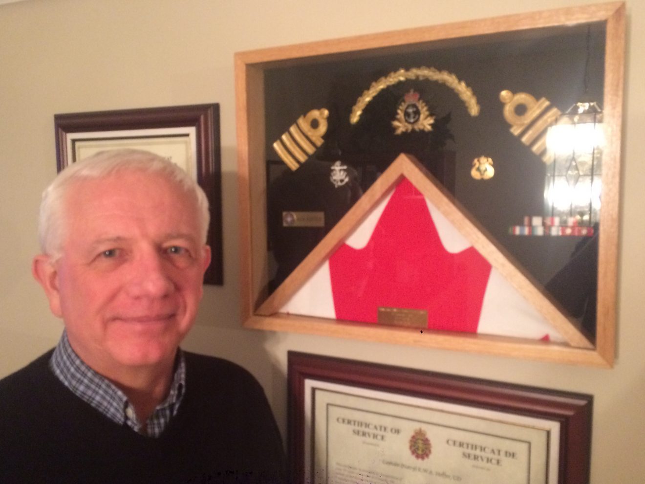 Ken Hoffer, founder of the Society of Atlantic Heroes, poses before Navy memorabilia at his home in Dartmouth 