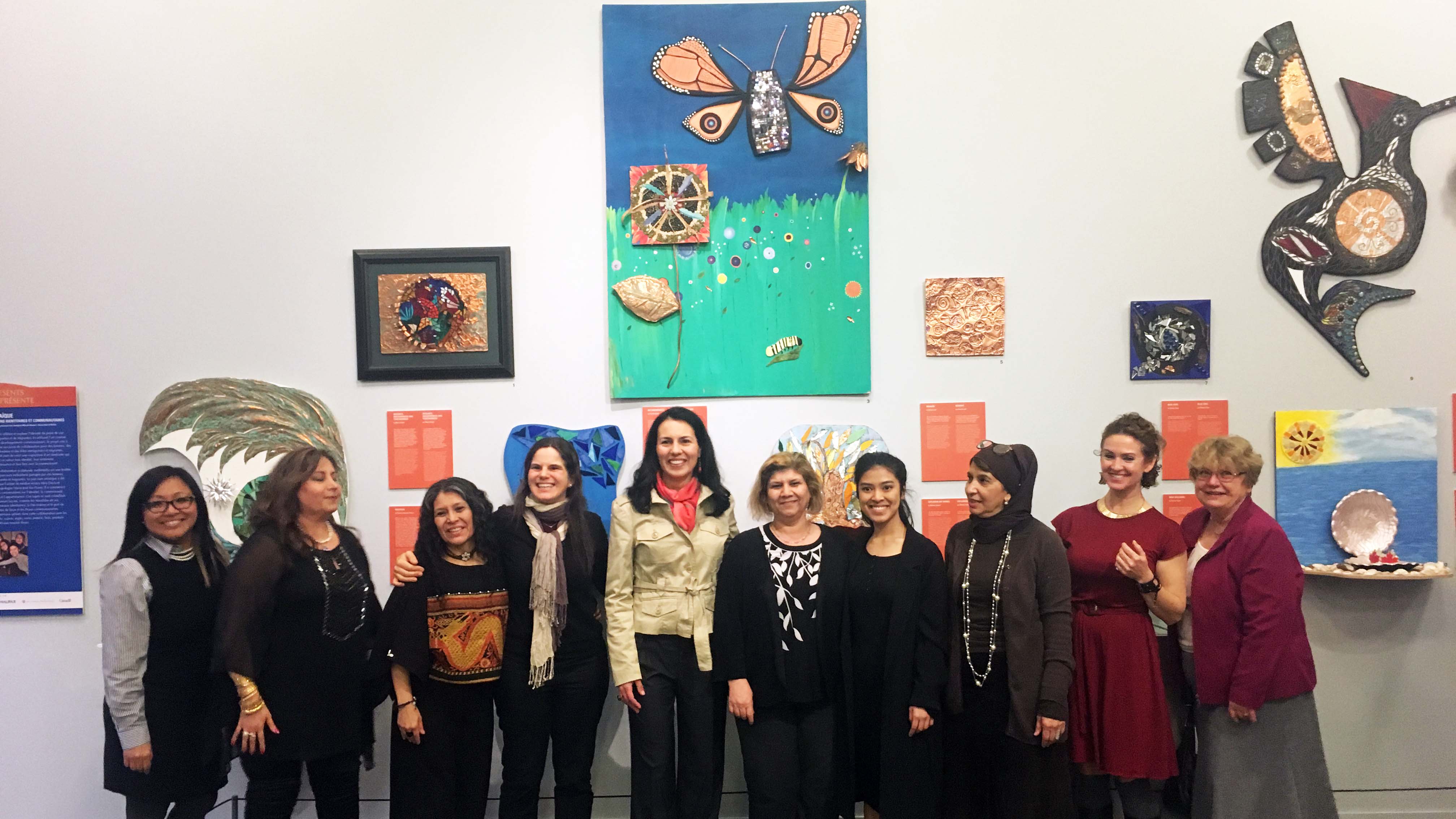 Ten women artists are in front of their mosaic arts.