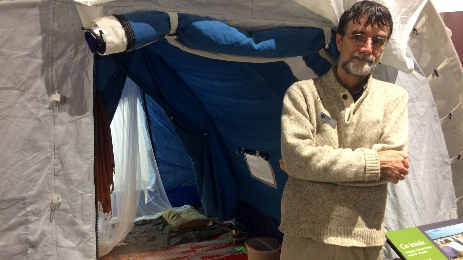 Museum curator Dan Conlin stands alongside a UNHCR tent featured in Refuge Canada exhibit
