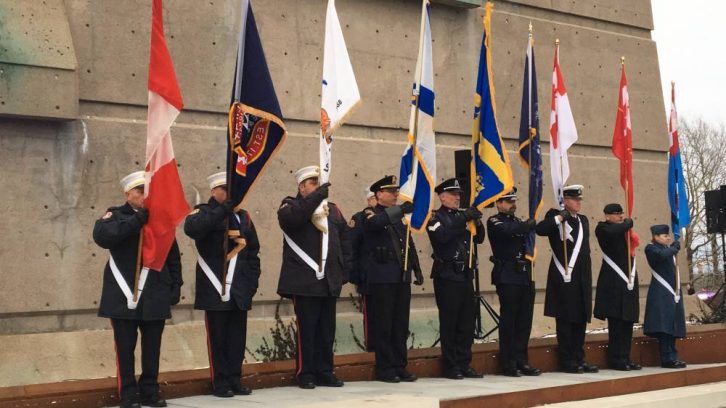 Military members hold flags in front of the Fort Needham Bell Tower during a ceremony marking the 101st anniversary of the Halifax Explosion.