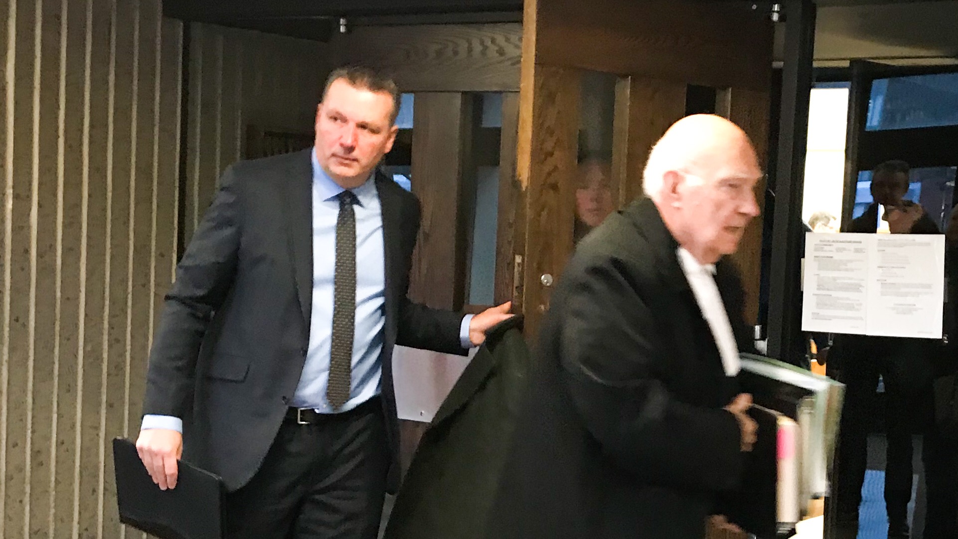 Two men are walking out of a courtroom.
