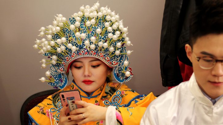 A woman checks her phone in a dressing room while waiting to perform at a gala on Feb. 2.