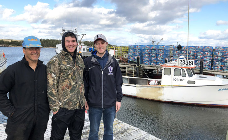 Kenny Henneberry stands with his sons Logan and Garrett in front of his brother's fishing boat at their family wharf in Sambro, N.S.