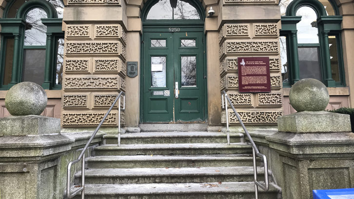 The main entrance to Halifax Provincial court. On the left door, there is a paper sign showing where to go for a ramp entrance. The sign cannot be read without climbing stairs. 