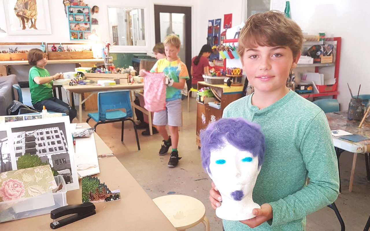 Ira Selfridge poses with his Open Studio creation - a foam head with purple hair and a goatee. His mother, Susanna Fuller, is a member of Imagine Bloomfield and a supporter of community spaces like Wonder’neath.