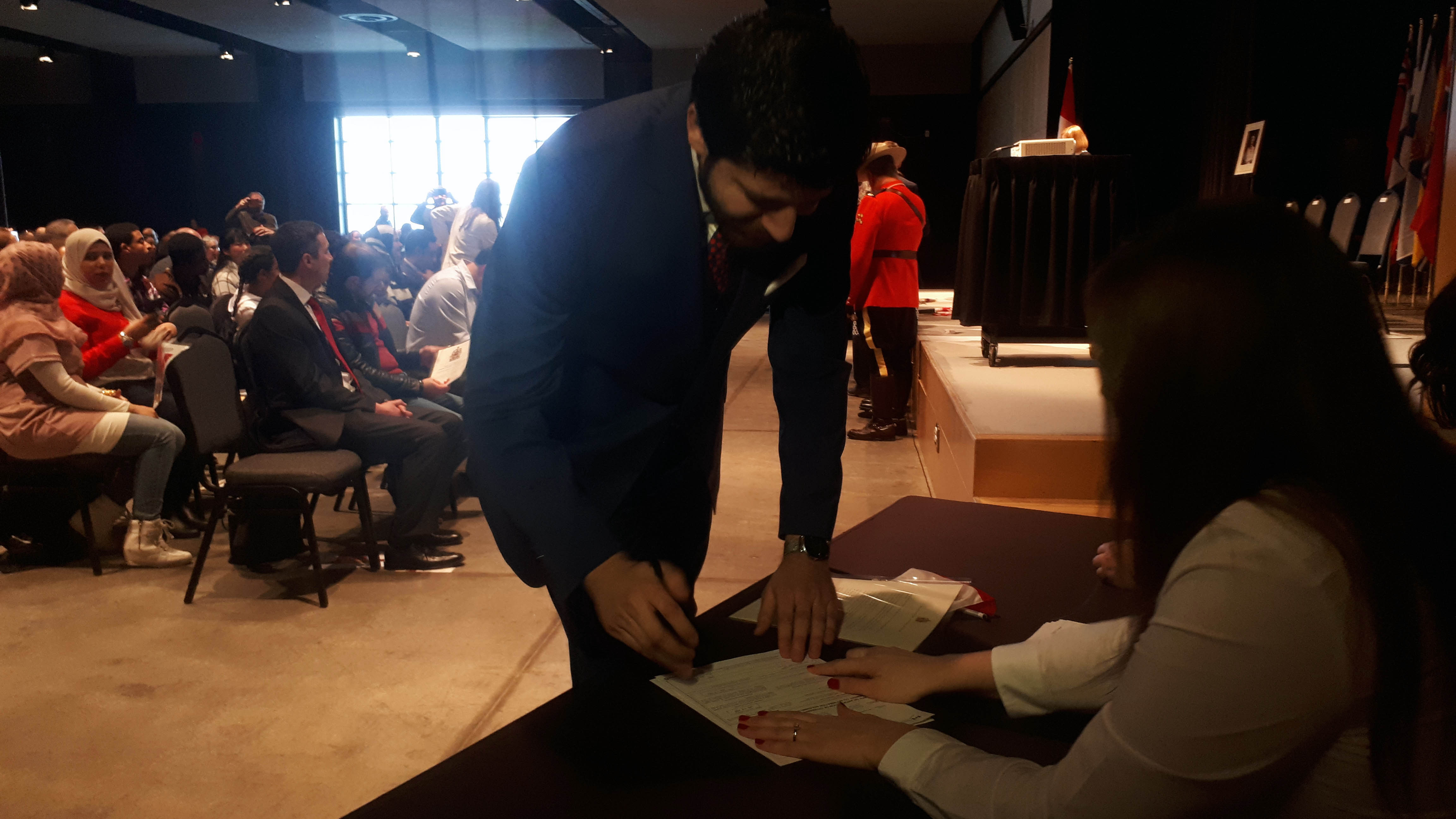 Peace by Chocolate CEO Tareq Hadhad signs his Canadian citizenship.