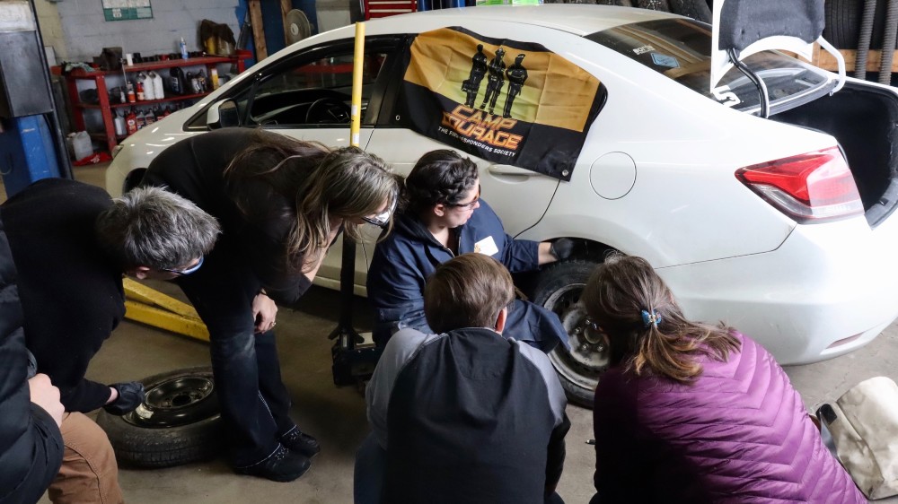 Robin Croft shows automotive workshop participants how to check tire pressure at Coast Tire and Auto Service in Dartmouth on March 8. The workshop was run by Camp Courage.