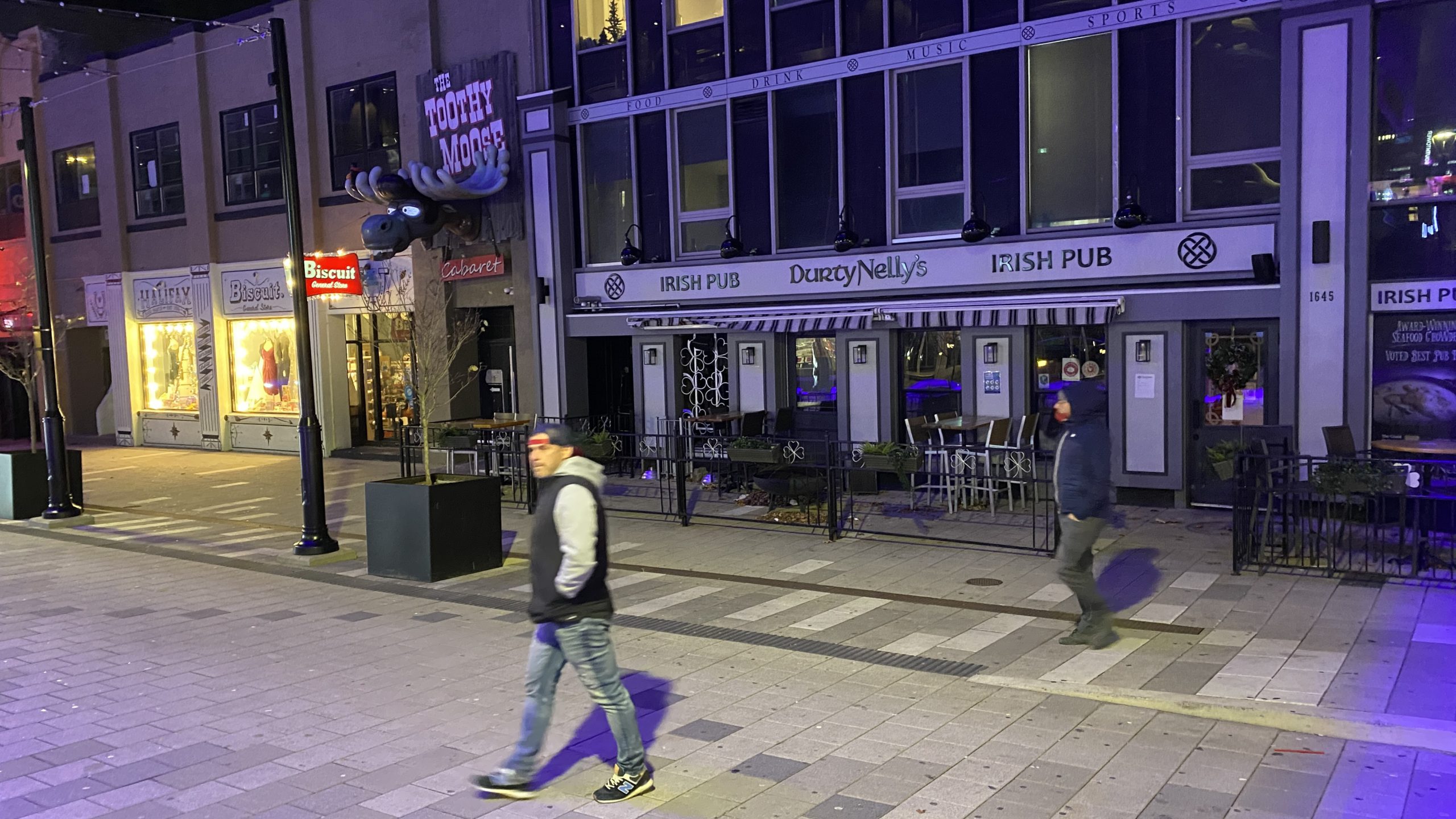 Pedestrians cross in front of a closed Durty Nelly’s Irish Pub in Halifax's deserted entertainment district Tuesday night.