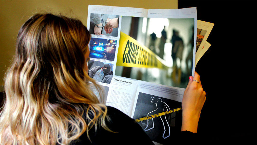 A reader looks over a newspaper full of crime in this photo illustration.