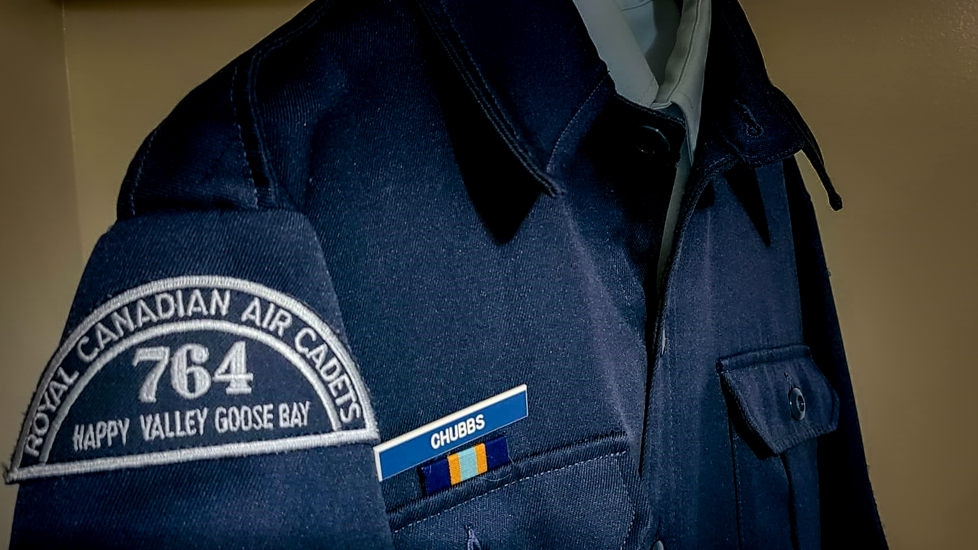 An unused air cadet uniform hangs in a closet.