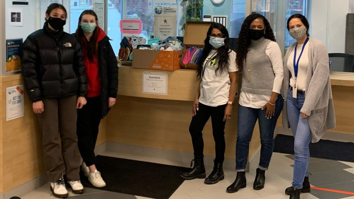Grace El Hawary (far left) and Isabelle Drohan (second from left) hand over the masks to the NECHC at the end of their campaign. 