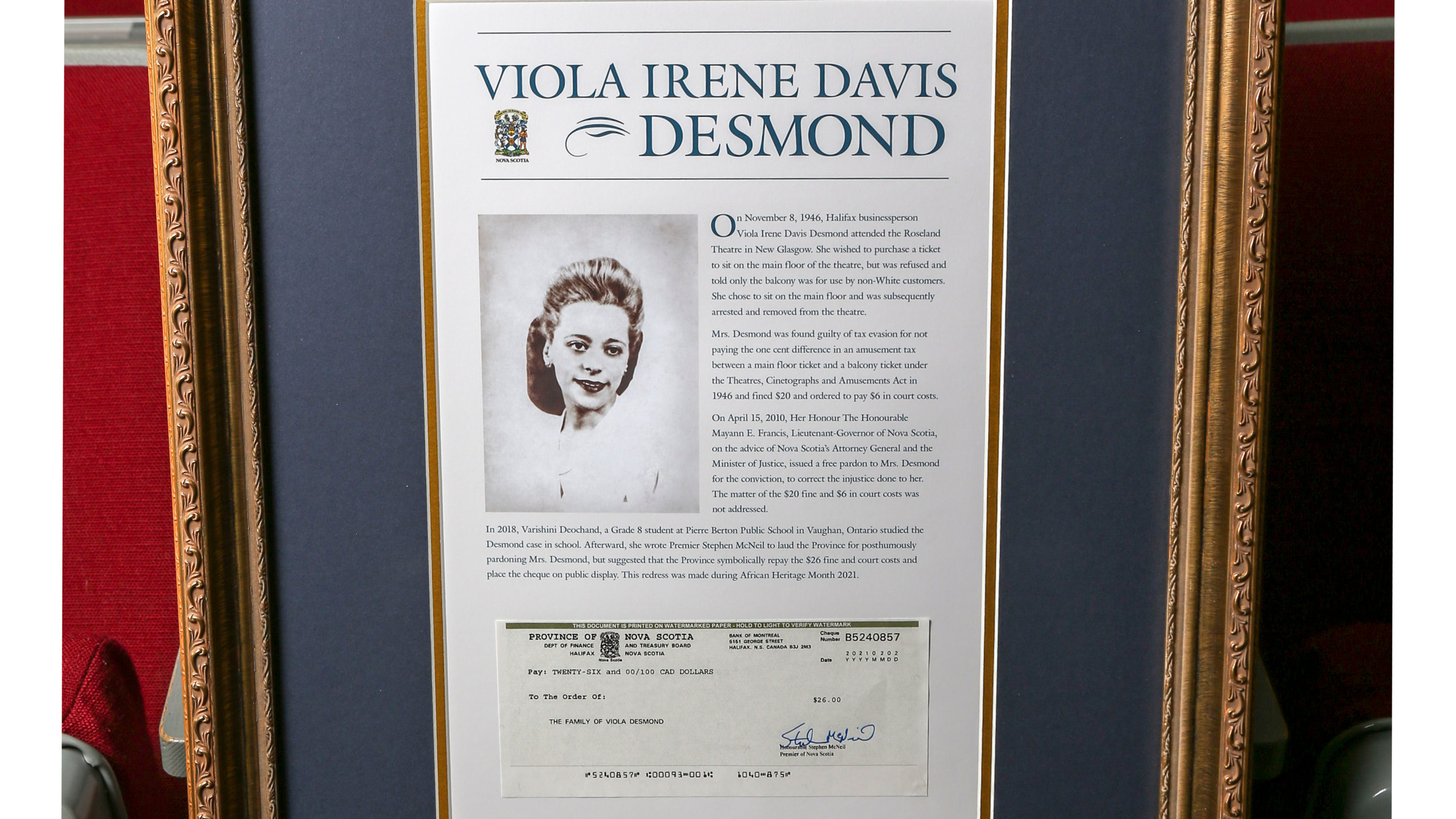 A framed copy of the official repayment cheque issued to the family of Viola Desmond is displayed alongside her pardon certificate.