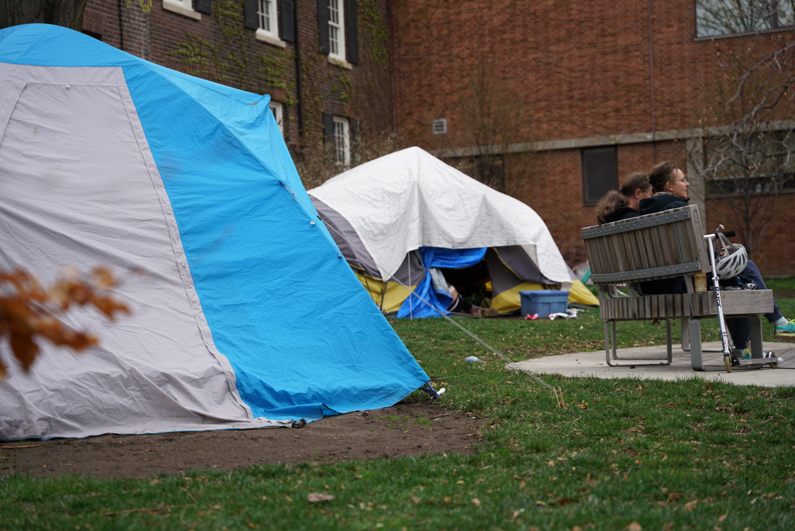 An image of two tents in Grange Park behind a two people seated on a bench