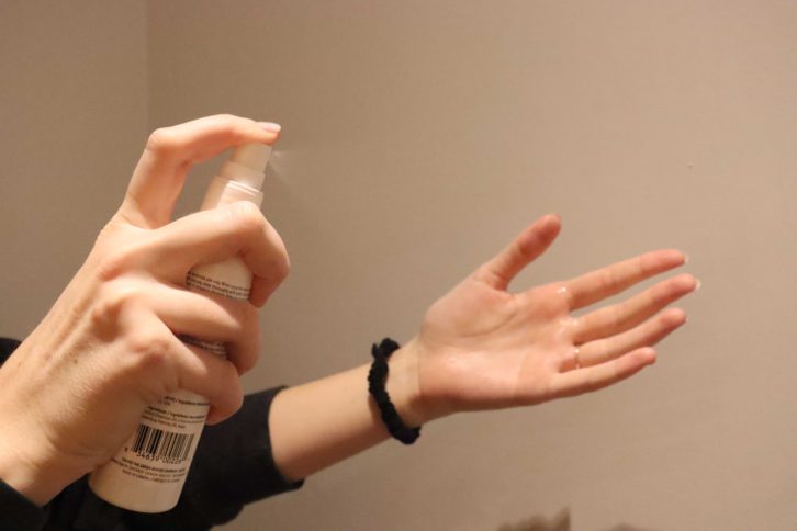 Photo illustration. A woman sprays hand sanitizer.