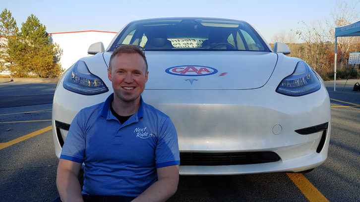 Robert Purcell poses in front of a Tesla Model 3 during a Next Ride test-drive event on Tuesday.