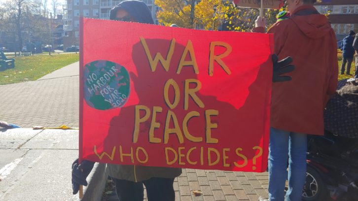 "War or peace, who decides?" A demonstrator's sign calls for Canadians to dwell on the question.