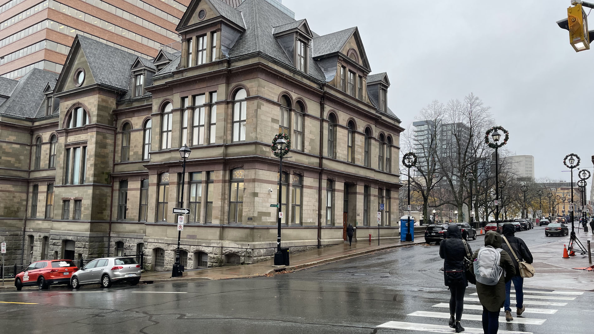 Pedestrians cross a rainy sidewalk at Halifax City Hall on Tuesday.