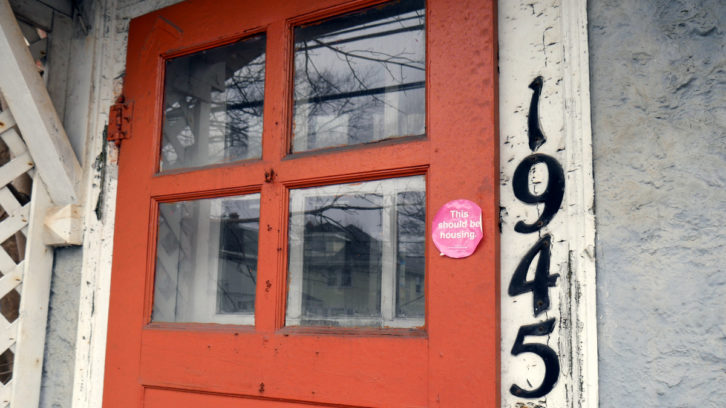 The front door of 1945 Oxford St. adorned with a 'This Should be Housing' sticker.