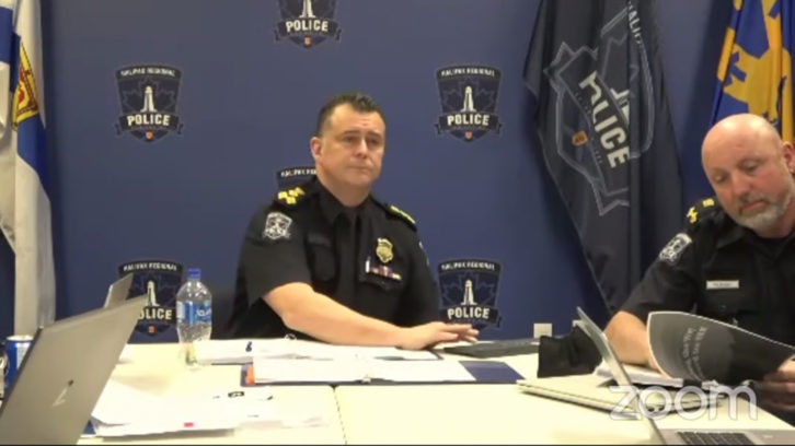 In this screenshot, Halifax Regional Police Chief Dan Kinsella (centre) and Deputy Chief Reid McCoombs listen to an online police board meeting. McCoombs looks through what appears to be the subcommittee's report on defunding the police. 