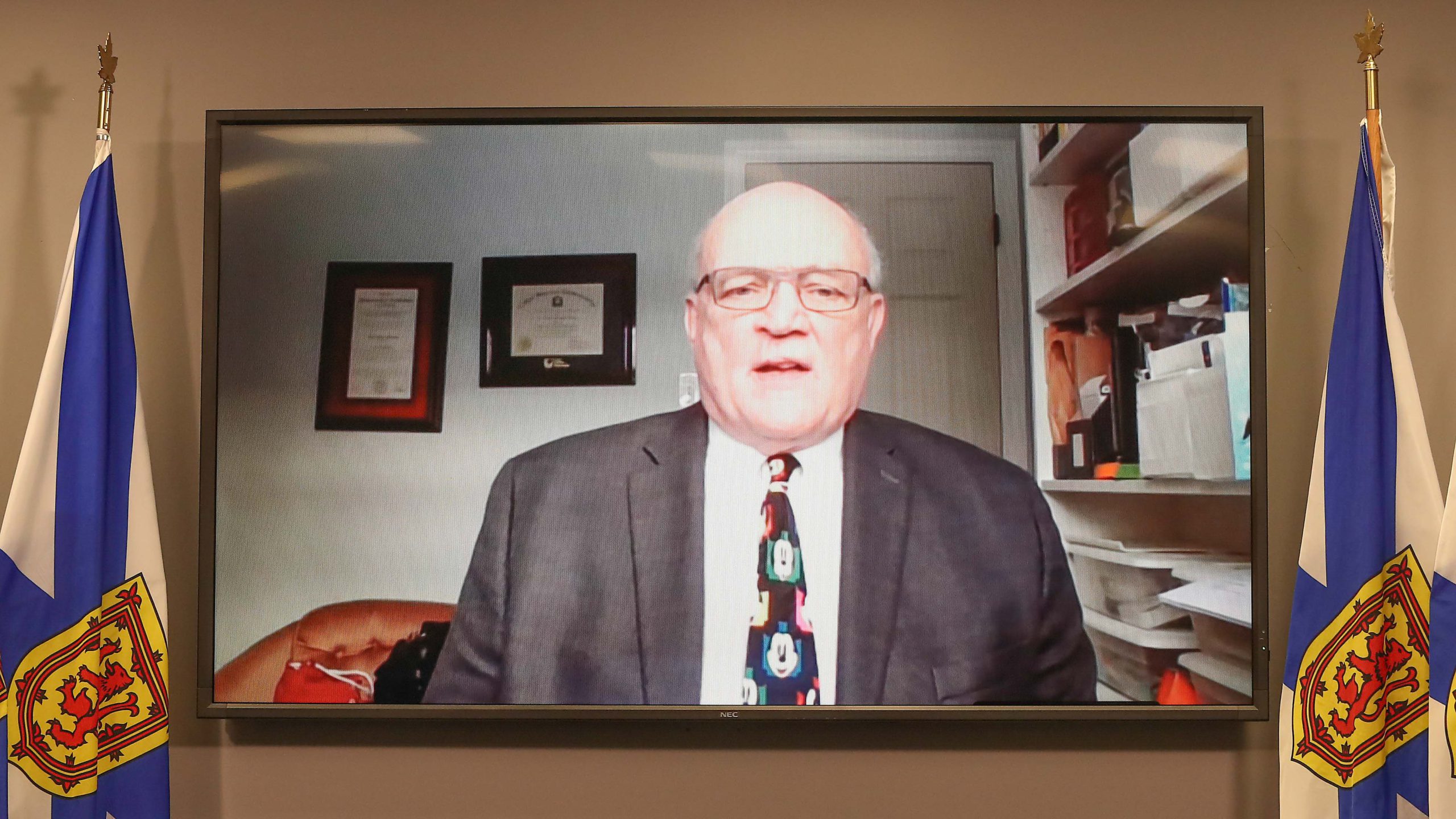 Dr. Robert Strang is seen on a TV screen between Nova Scotian flags.