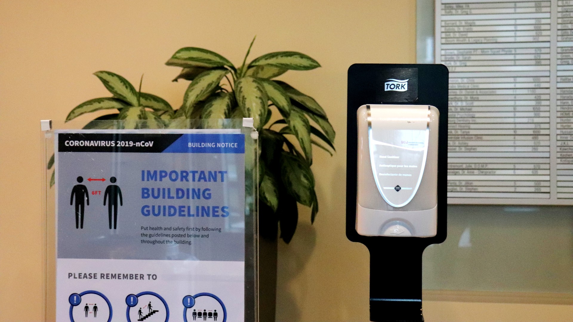 A sign in the Halifax Professional Centre reminds people to maintain social distance to help curb the spread of COVID-19, next to a hand sanitizing station. 